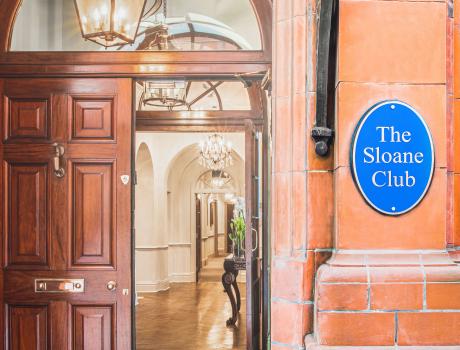 Open door to The Sloane Club with blue plaque on the right reading 'The Sloane Club'