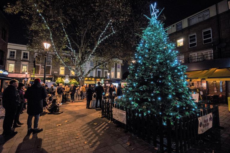 A Christmas tree in a pedestrianised square with people around it