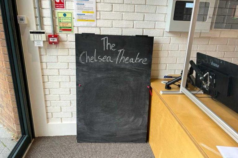 A chalkboard in a room that has Chelsea Theatre written on it