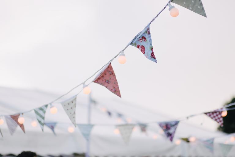 Bunting strung with fairy lights against grey sky