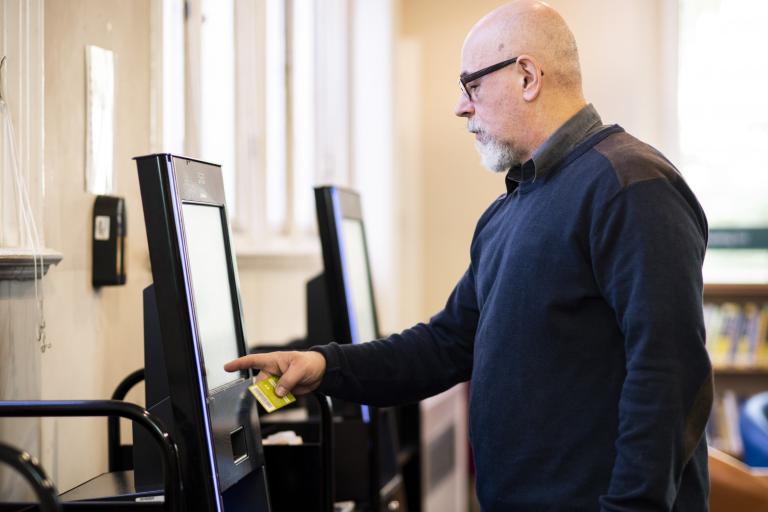 A man using the self-service screens in the library