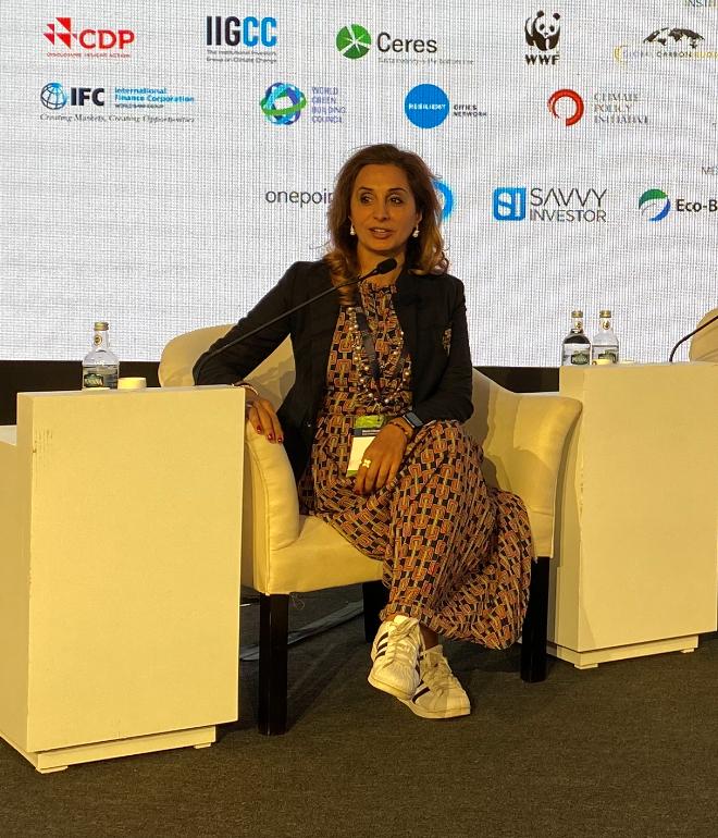 Farzana Khan sitting on a chair at a conference 