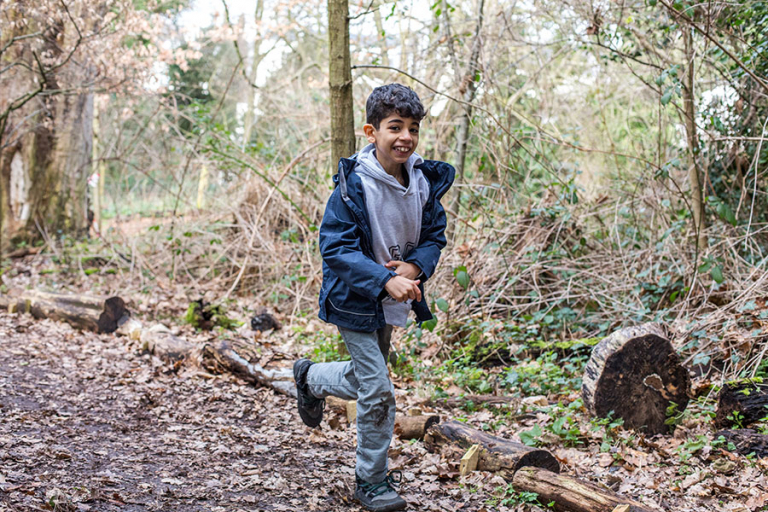 Picture of a boy having fun running through the woodland.